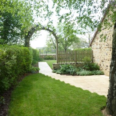 Jardin avec du gazon et une arche en bois