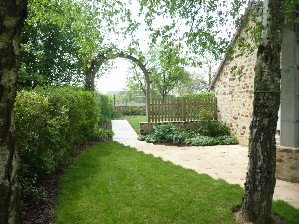 Jardin avec du gazon et une arche en bois