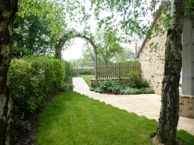 Jardin d'un particulier avec du gazon et une arche en bois