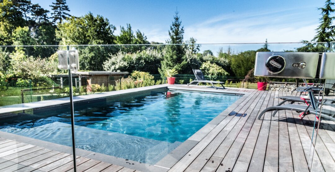 Jardin avec piscine, plantations, terrasse en bois et mobilier