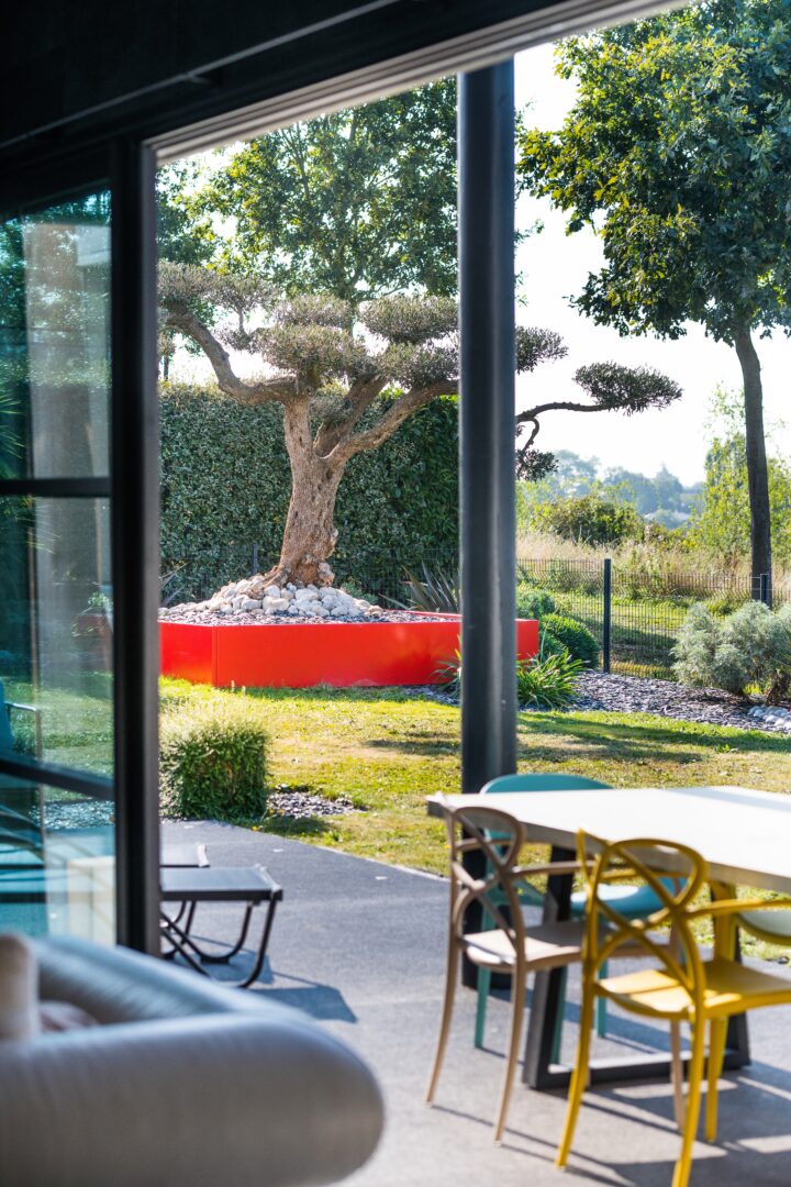 Jardin avec une terrasse en grès cérame, des plantations et du mobilier