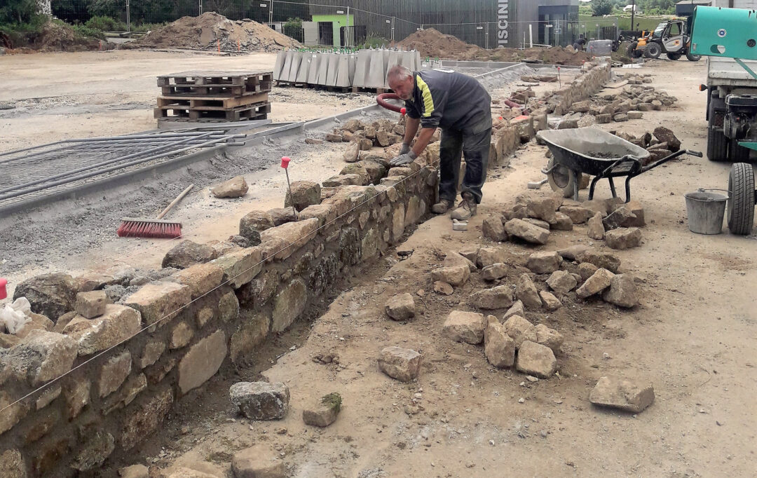 Salarié qui construit un mur en pierre